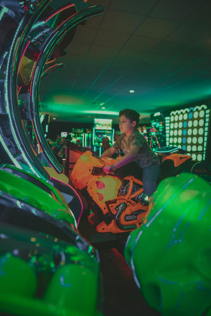 Child enjoying racing arcade game during lifestyle birthday photography session in Connecticut