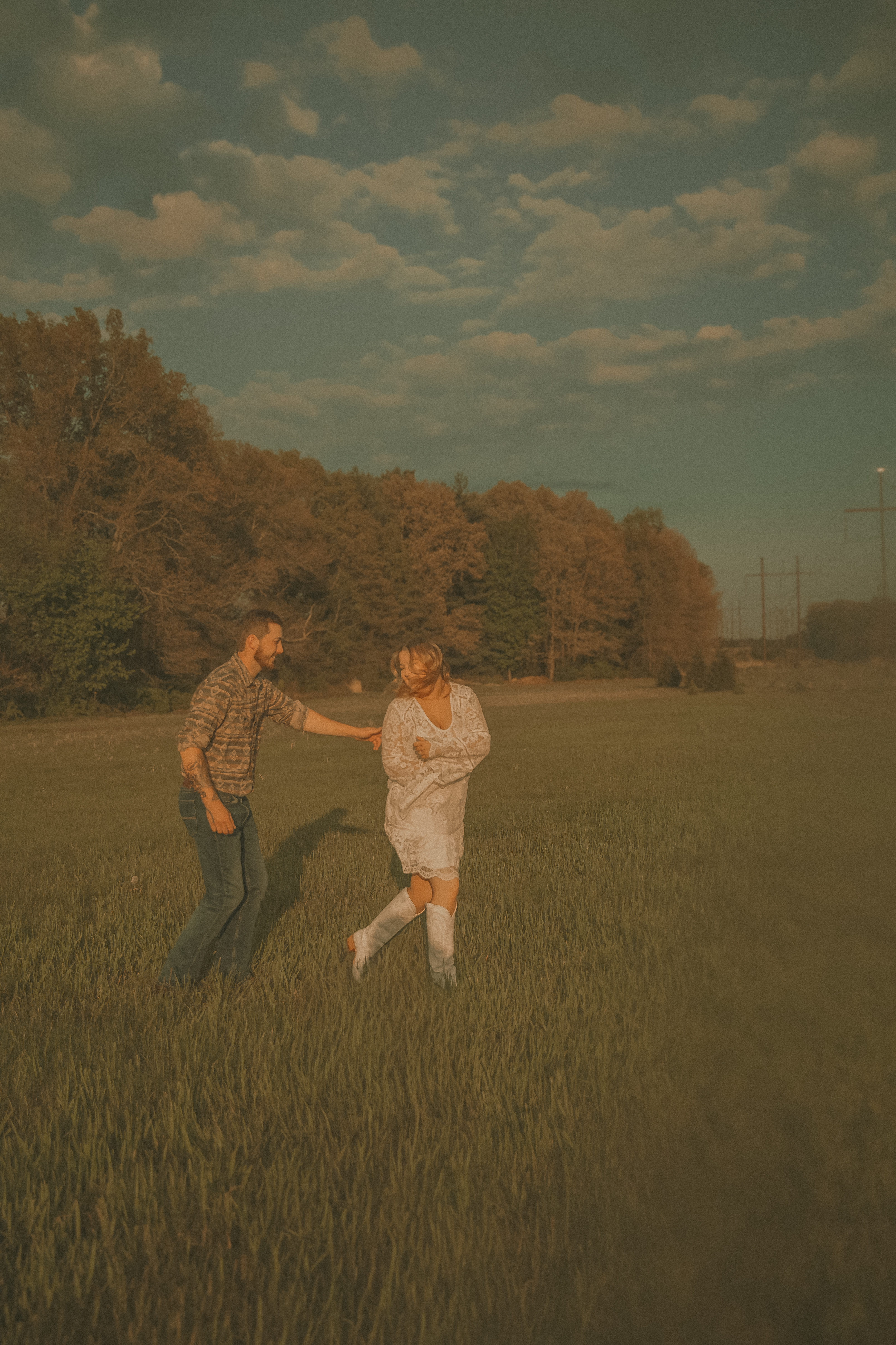 Couple dancing and laughing together in an open green field at golden hour in Connecticut