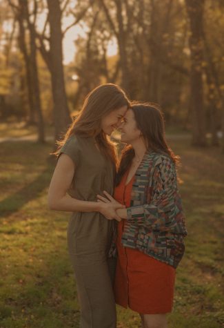 Connecticut engagement photographer captures two women smiling forehead to forehead while holding hands on a tree-lined path during a warm golden hour session