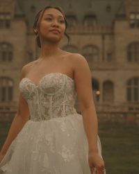 Connecticut wedding photographer captures a close-up portrait of a bride in a strapless lace corset gown gazing upward in front of a stone estate facade