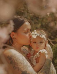 Mother kissing baby surrounded by spring blossoms during motherhood session in West Hartford Connecticut